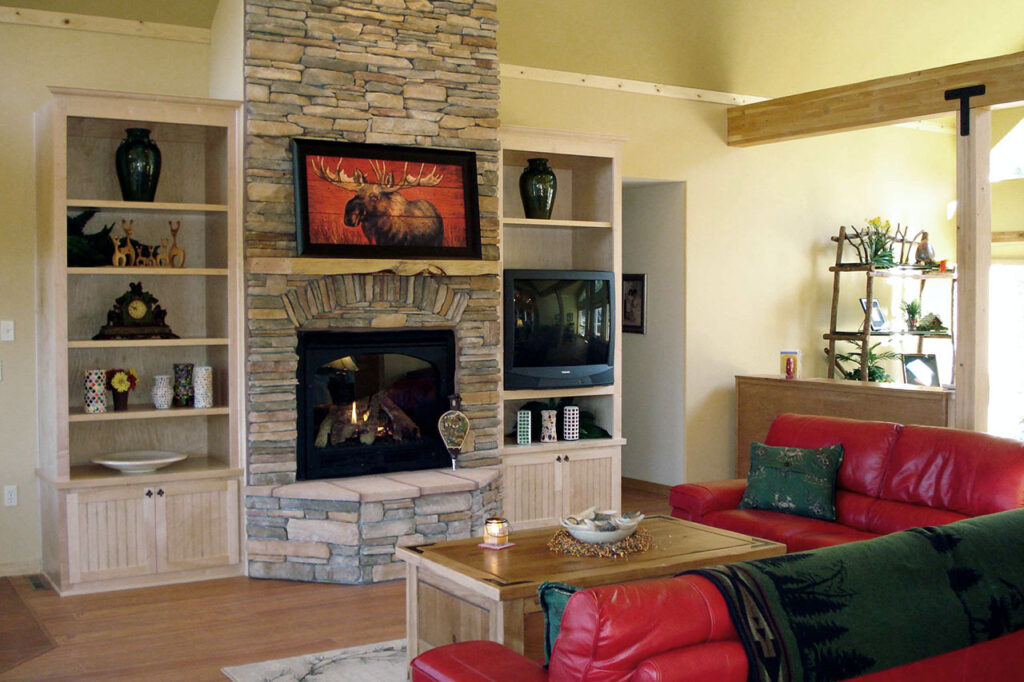 LIVING ROOM WITH STONE FIREPLACE, BUILT-IN BOOKCASES, AND WOOD FLOORING