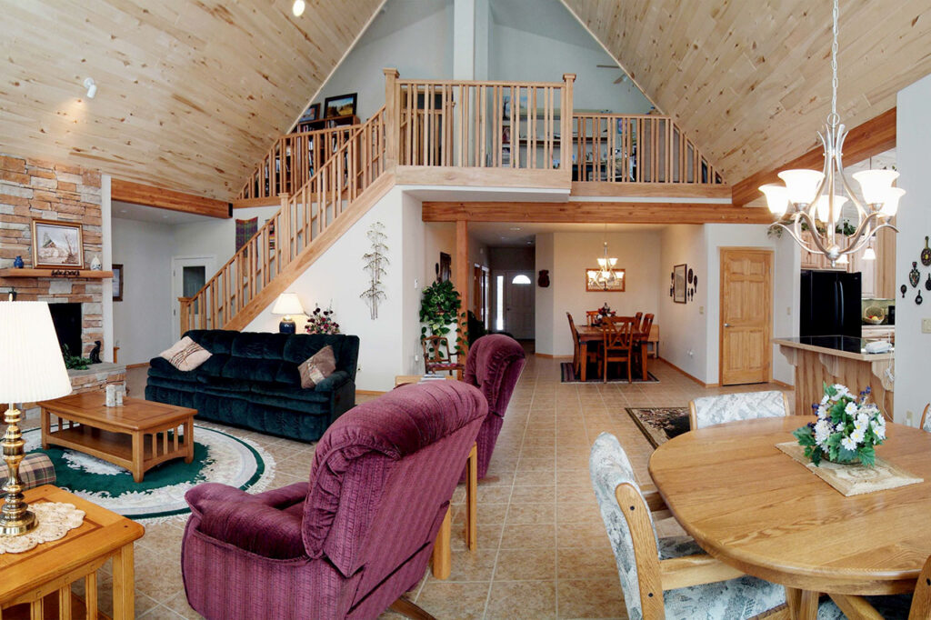 LIVING ROOM WITH STONE FIREPLACE, CUSTOM STAIR RAILING, AND CERAMIC TILE FLOORS