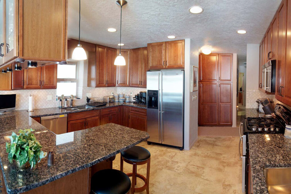 KITCHEN WITH SOLD GRANITE COUNTERTOPS, UNDER CABINET LIGHTING, AND DECORATIVE PENDANT LIGHTING